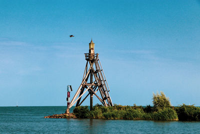 View of tower by sea against sky