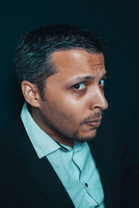 Portrait of man looking away against black background