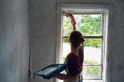 Rear view of woman standing against wall