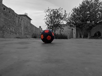 Soccer ball on field by wall against sky