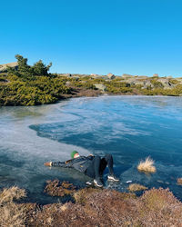 Scenic view of sea against clear sky with woman laying on frozen river