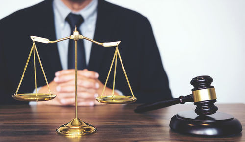 Midsection of lawyer with weight scale and gavel at table