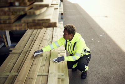 Full length of young female worker arranging planks at lumber industry