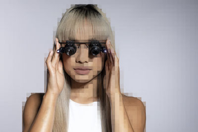 Pixelated young woman adjusting magnifying eyeglasses over white background