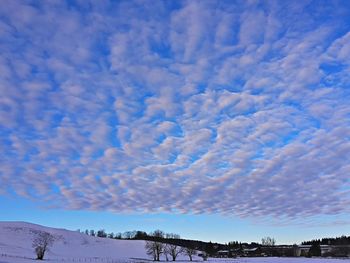 Snow covered landscape against cloudy sky