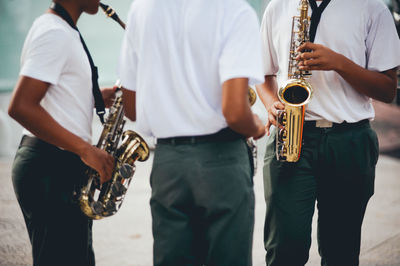 Midsection of men playing saxophones