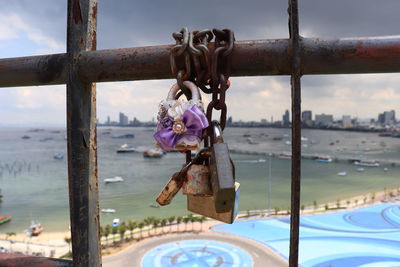 Close-up of padlocks on railing against sky