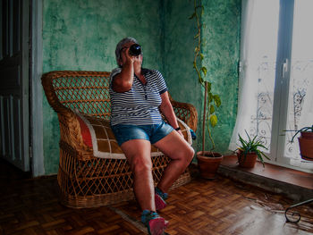 Woman drinking wine on chair at home