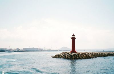 Lighthouse by sea against sky