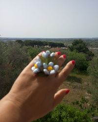 Cropped image of hand holding sea against clear sky