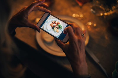High angle view of mature woman photographing food at dining table in dinner party