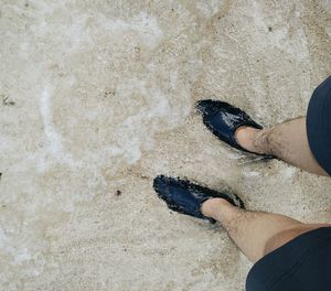 Low section of man standing on sand