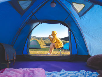 Rear view of woman sitting at tent