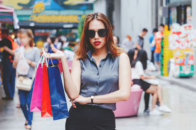 Portrait of young woman with shopping bags outside in mall