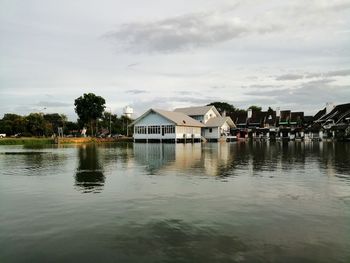 Houses by lake and buildings against sky