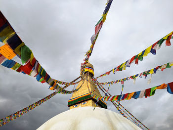 Low angle view of temple tower with flags against sky