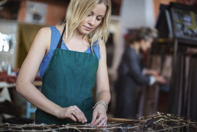 Young female worker making chaise longue at workshop