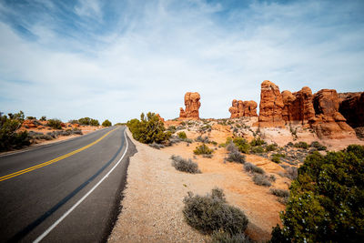 Road leading towards rock formation against sky