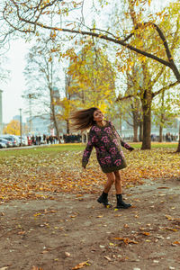 Woman tossing hair while standing at park during autumn
