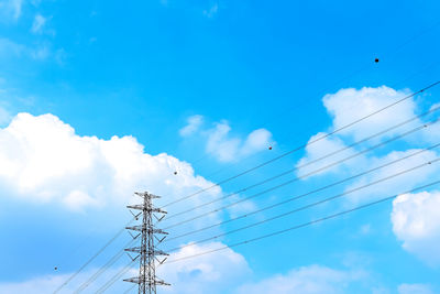 Low angle view of electricity pylon against blue sky