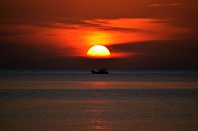 Silhouette boat in sea against orange sky