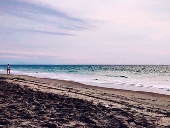 Scenic view of beach against cloudy sky