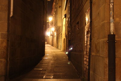 Empty walkway along buildings at night