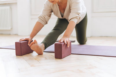 Attractive middle aged woman in sportswear ptactice yoga with equipment in light studio