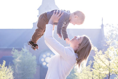 Low angle view of woman with arms raised standing against sky