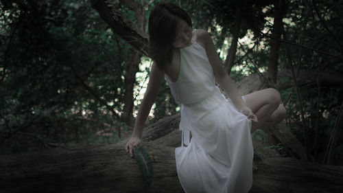 Woman standing by tree trunks in forest