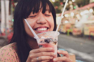 Smiling woman holding drink outdoors