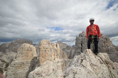 Rear view of man standing on rock against sky