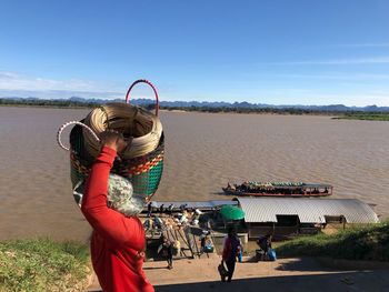 Person carrying basket against river