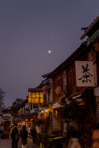 People on street against illuminated buildings at night