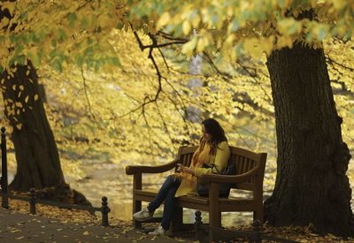 Young woman sitting on bench in park