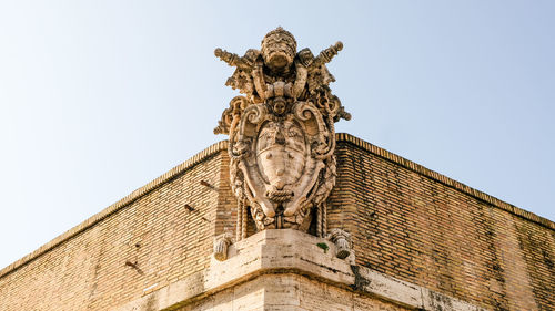 Low angle view of statue against building against sky