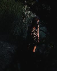 Woman standing in forest at night