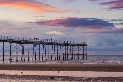 Bridge over sea against sky during sunset