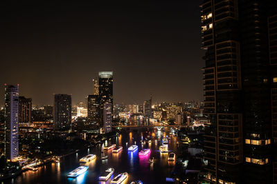 Illuminated buildings in city against sky at night