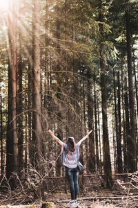 Full length of woman standing by tree in forest