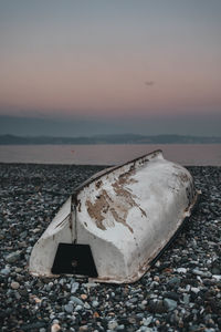 Abandoned boat on beach during sunset