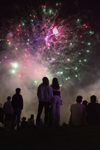 Silhouette people standing against illuminated sky at night