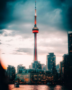 Communications tower in city against sky