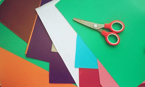 High angle view of multi colored papers and scissors on table