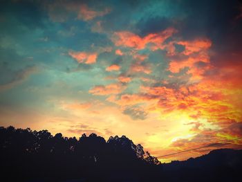 Low angle view of silhouette trees against dramatic sky