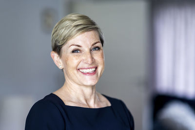 Smiling woman with short blond hair at home