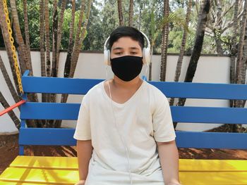 Bored brazilian boy using mask and headphones posing to the camera.