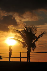Silhouette people against sea during sunset