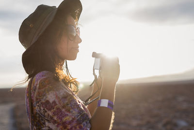 Chile, san pedro de atacama, woman with camera in the desert in backlight