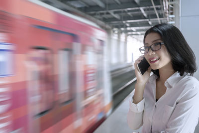 Woman talking on mobile phone at railroad station platform